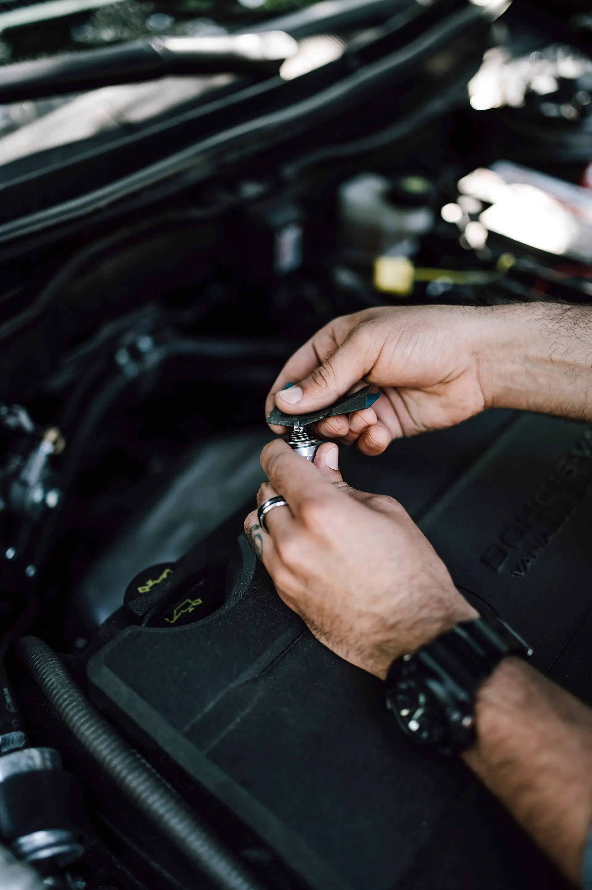 Manos de un mecánico trabajando bajo el capó de un auto